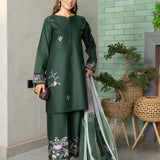 Woman in a green traditional outfit with floral patterns, holding a dupatta, against a light green tiled wall.